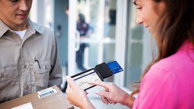 Woman signing for package using Square Reader on smart phone with her Visa card for payment.