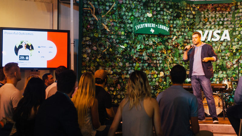 Man presents on stage at Visa's Everywhere lounge in Texas. 